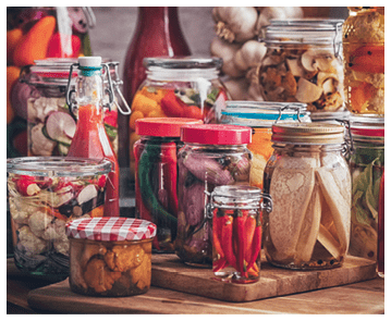 Preserving organic vegetables in jars like carrots, cucumbers, tomatoes, mushrooms, red onions and bok choy 