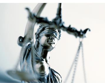 A close up and a low angle view of a statue of lady justice. The image is photographed with a very shallow depth of field with the focus being on her face.