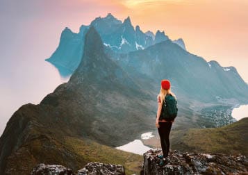 Traveler woman hiking outdoor in Norway travel adventure vacations healthy lifestyle girl hiker with backpack enjoying sunset mountains view