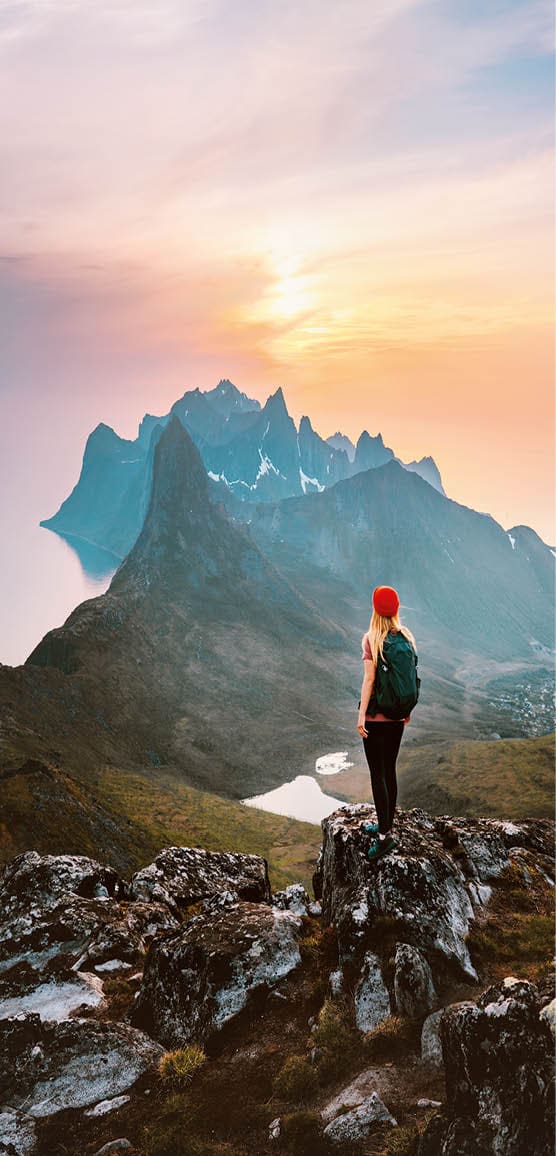 Traveler woman hiking outdoor in Norway travel adventure vacations healthy lifestyle girl hiker with backpack enjoying sunset mountains view