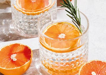 Summer orange cocktails with fresh citrus fruits. Hard seltzer, lemonade, refreshing drinks, low alcohol mocktails, summer party concept. Shadow and sunlight. Banner, flat lay, top view, copy space